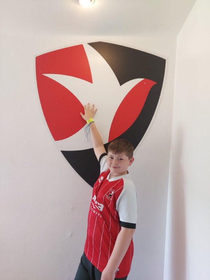 Noah from Alderman Knight School, touching the famous Cheltenham Town FC Badge at the Completely-Suzuki Stadium